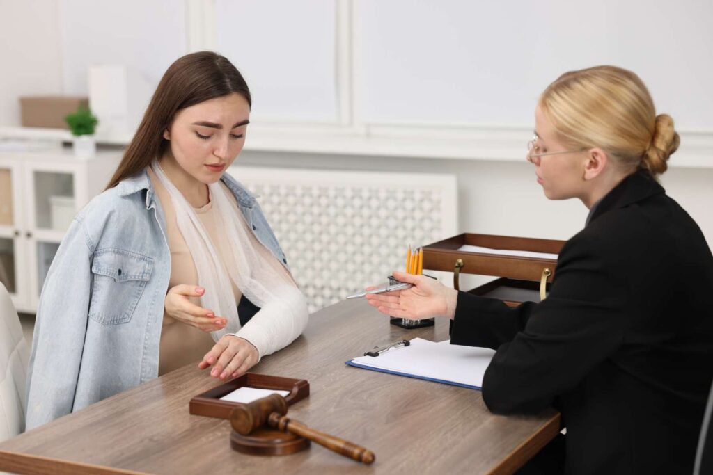 An injured woman meeting with a lawyer in an office at Sammons Injury Law.