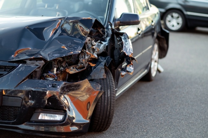 Front-left collision damage on a black car with a broken headlight in Apollo Beach, FL