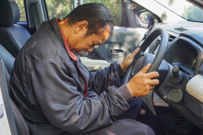 Driver seated with head down, gripping the steering wheel, showing fatigue in Apollo Beach, FL